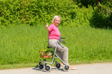 Smiling elderly woman holds thumbs up while seated