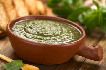 Frischer Pesto aus Spinat, Basilikum und Knoblauch in rustikaler Schüssel mit getoastetem Brot an...
