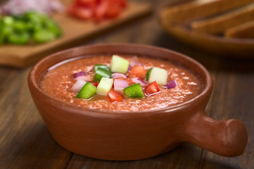 Spanische kalte Gazpacho Gemüsesuppe zubereitet aus Tomaten, Gurken, Paprika, Zwiebel, Knoblauch und Olivenöl (Selektiver Fokus, Fokus auf die vorderen Gemüsestückchen auf der Suppe)