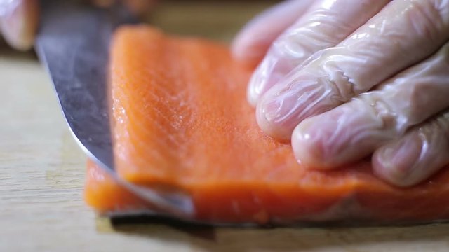 Sushi chef slicing fresh salman steak in studio