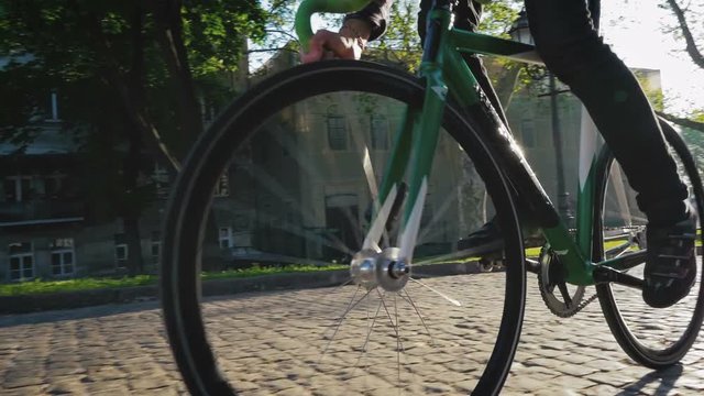 Young hipster man riding gixed gear bike in old city center, slow motion