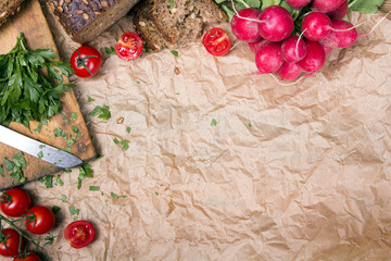 Kitchen background with baking paper, tomatoes, radish and parsley