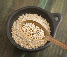 Pearl mijo in bowl and wooden spoon.