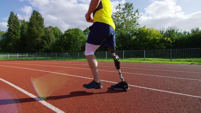  Disabled athlete with prosthetic leg running at the running track