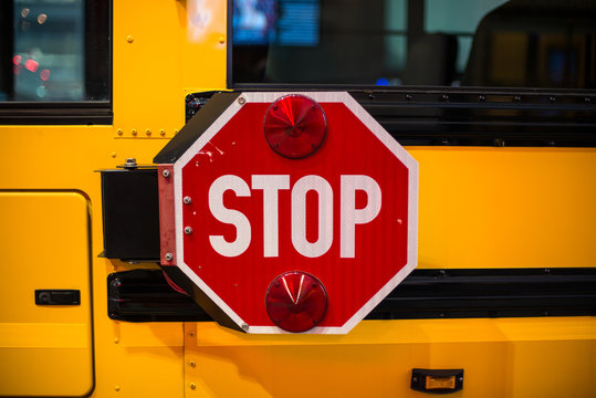 Stop sign on side on yellow School Bus.
