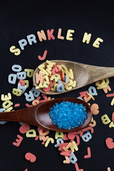 Colorful sugar lettered sprinkles in wooden spoons. Vertical image.