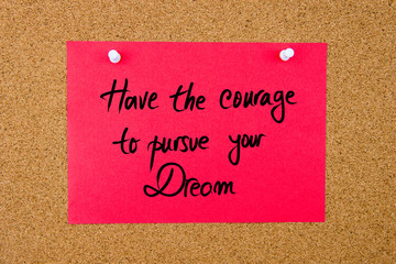 Red paper note with handwritten text on cork board