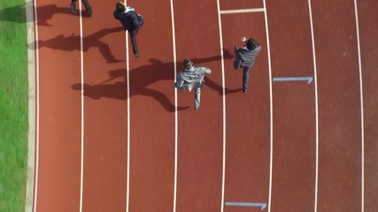  Drone footage of competitive businessmen racing each other at running track
