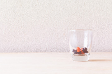 Pill in glass on wooden floor and concrete background