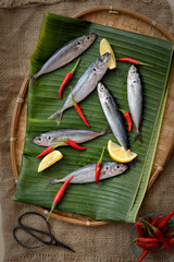Fresh fish, chili pepper and lemon banana leaf as background.
