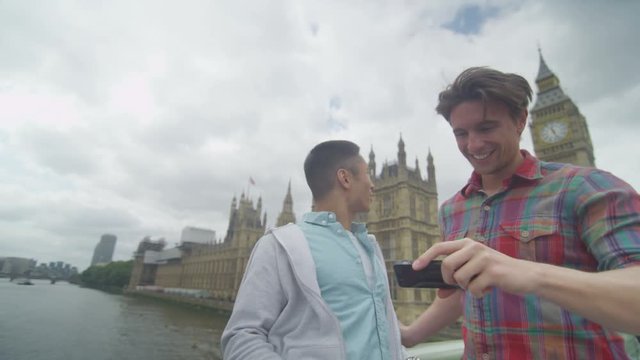 Male friends pose to take a selfie in front of London Houses of Parliament