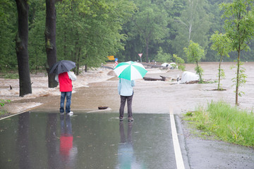 Klimawandel ? Hochwasser 2013 -  2 Passanten stehen auf der überfluteten Straße bei Regen und...