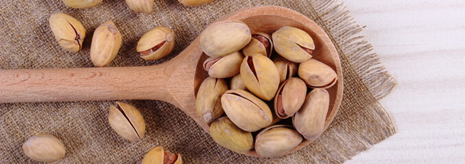 Pistachio nuts with spoon on white wooden table, healthy eating