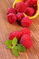 Fresh raspberries and lemon balm on wooden surface, healthy food