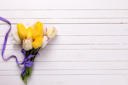 Bright yellow and white spring tulips on white wooden background