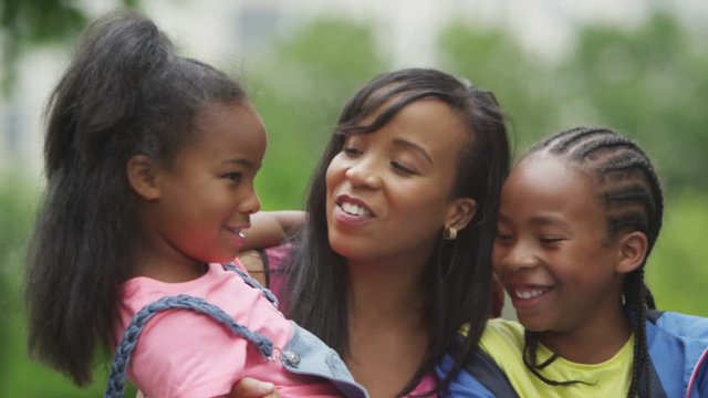  Portrait of happy African American mother & children having fun in the park. 