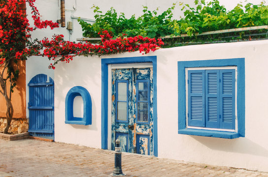 Facade of a very small white house with blue windows in Halkidiki, Greece
