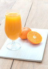 Glass of fresh orange juice with half orange on wooden table