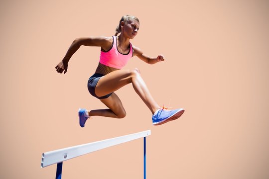 Composite image of sporty woman jumping a hurdle