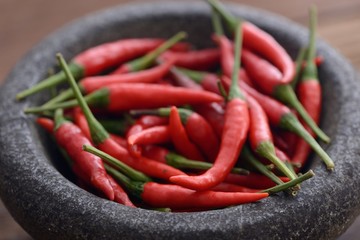 Heap of fresh red chili peppers in stone mortar