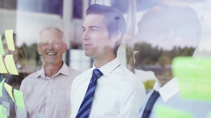  Mixed ethnicity business team brainstorming for ideas with sticky notes