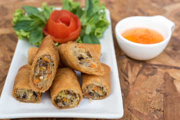 Closeup photo of egg rolls in Thai style with sweet sauce on wooden table, spring rolls or popiah