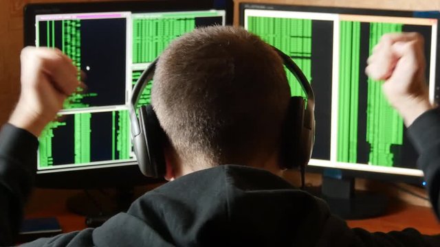 Hacker pleased with victory. Criminal hacker penetrating network system from his dark hacker room. 
