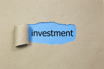 The word investment appearing behind torn paper