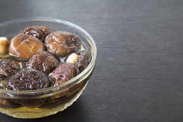 Dried Chinese mushroom in water on black wooden background.