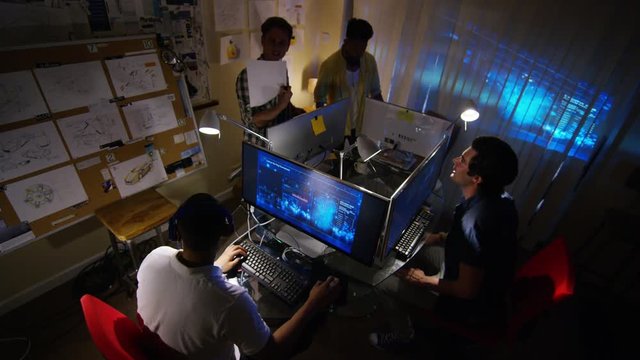  Young creative computer design team working together in dark office.