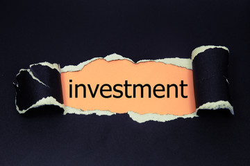 investment word written under torn paper. 