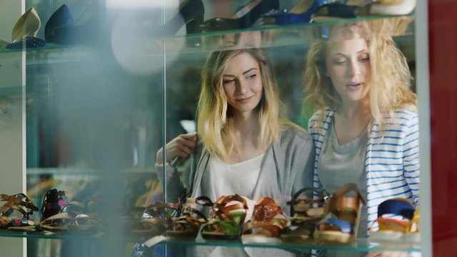 Two young women looking at a glass case a shoe store
