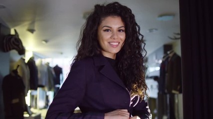  Beautiful woman wearing new suit & looking in the mirror in tailor's shop