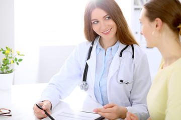 Doctor and  patient  sitting at the desk near window, sun shines