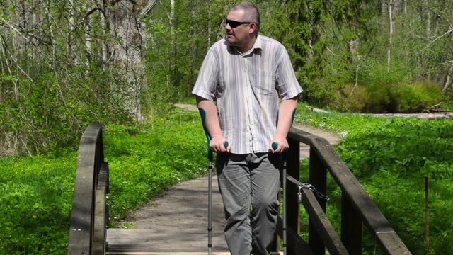 Disabled man with crutches walking on bridge

