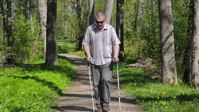Disabled man with crutches walking in park