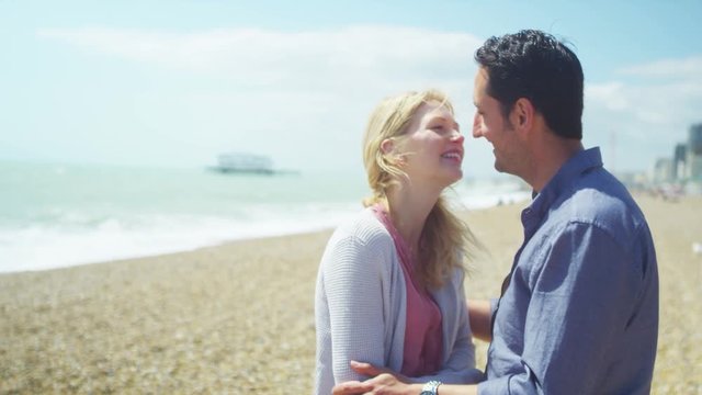  Portrait of romantic couple on beach, kiss & smile to camera. 