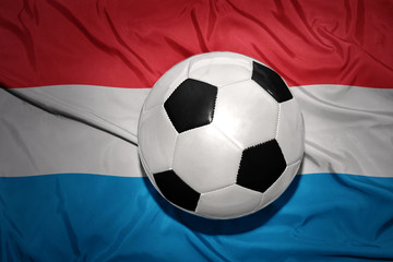 Naklejka premium black and white football ball on the national flag of luxembourg