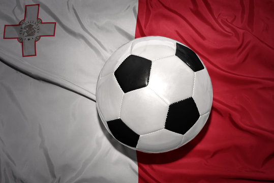 black and white football ball on the national flag of malta