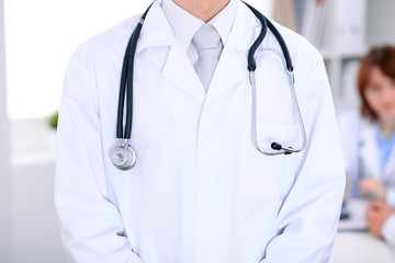 Close-up of a male doctor in a background of doctor and patient