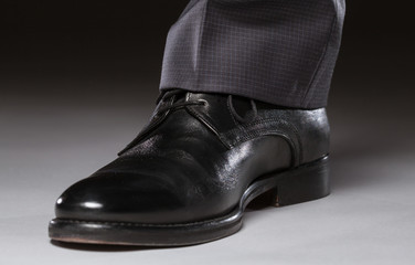 Male leg in black leather shoe