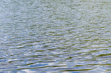 Water surface with ripples and sunrays reflections