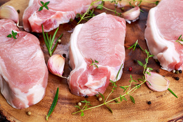 Raw Fresh Boneless Pork Chops with herbs. on wooden board.