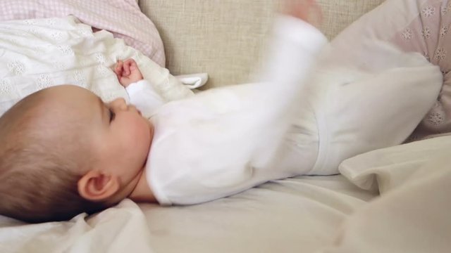 Baby Girl in White Playing On A Bed 
