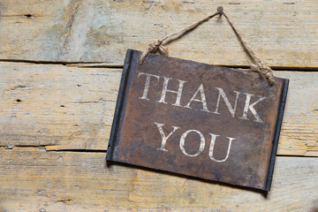 rusty metal sign on wooden table, text thank you
