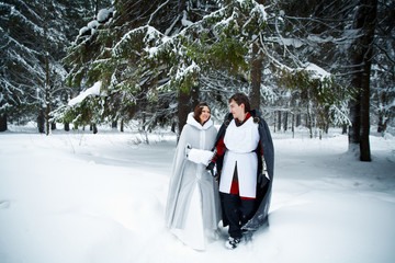 couple in medieval clothes in a snowy forest. Love concept for medieval design