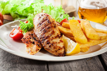 Grilled chicken breasts served with fries and fresh salad