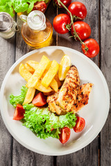 Grilled chicken breasts served with fries and fresh salad