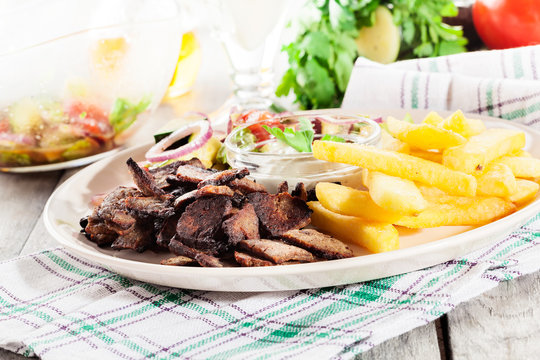 Grilled meat with French fries and fresh vegetables