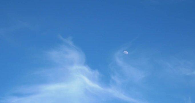 Moon Visible In Daylight Blue Sky With White Soft Clouds